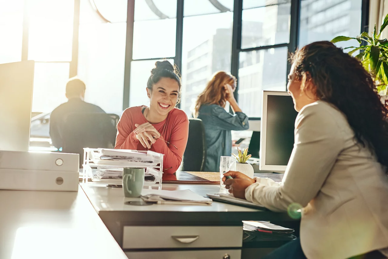 Zwei junge Geschäftsfrauen unterhalten sich und arbeiten in ihrem Büro