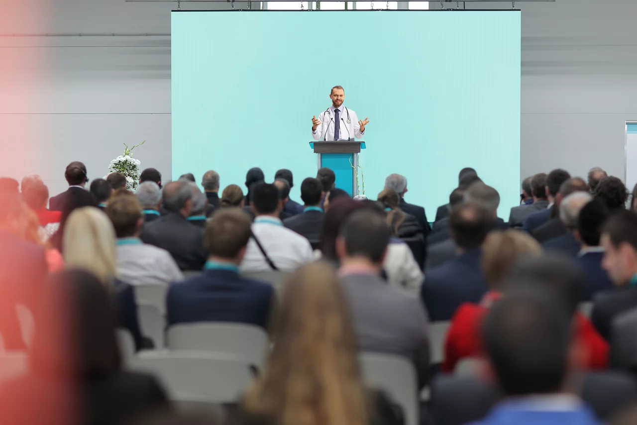 Doctor giving a speech on a podium at a conference in front of an audience
