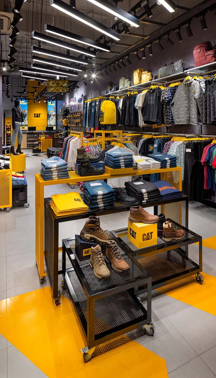 The interior of a CAT store, featuring merchandise displays for boots and apparel in an industrial black and yellow design.