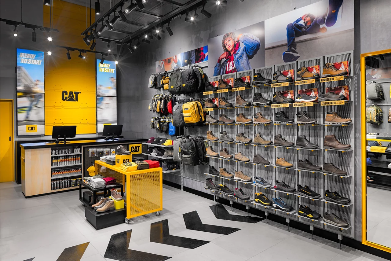 The interior of a CAT store, featuring the checkout counter and an extensive wall display of boots, shoes, and bags.