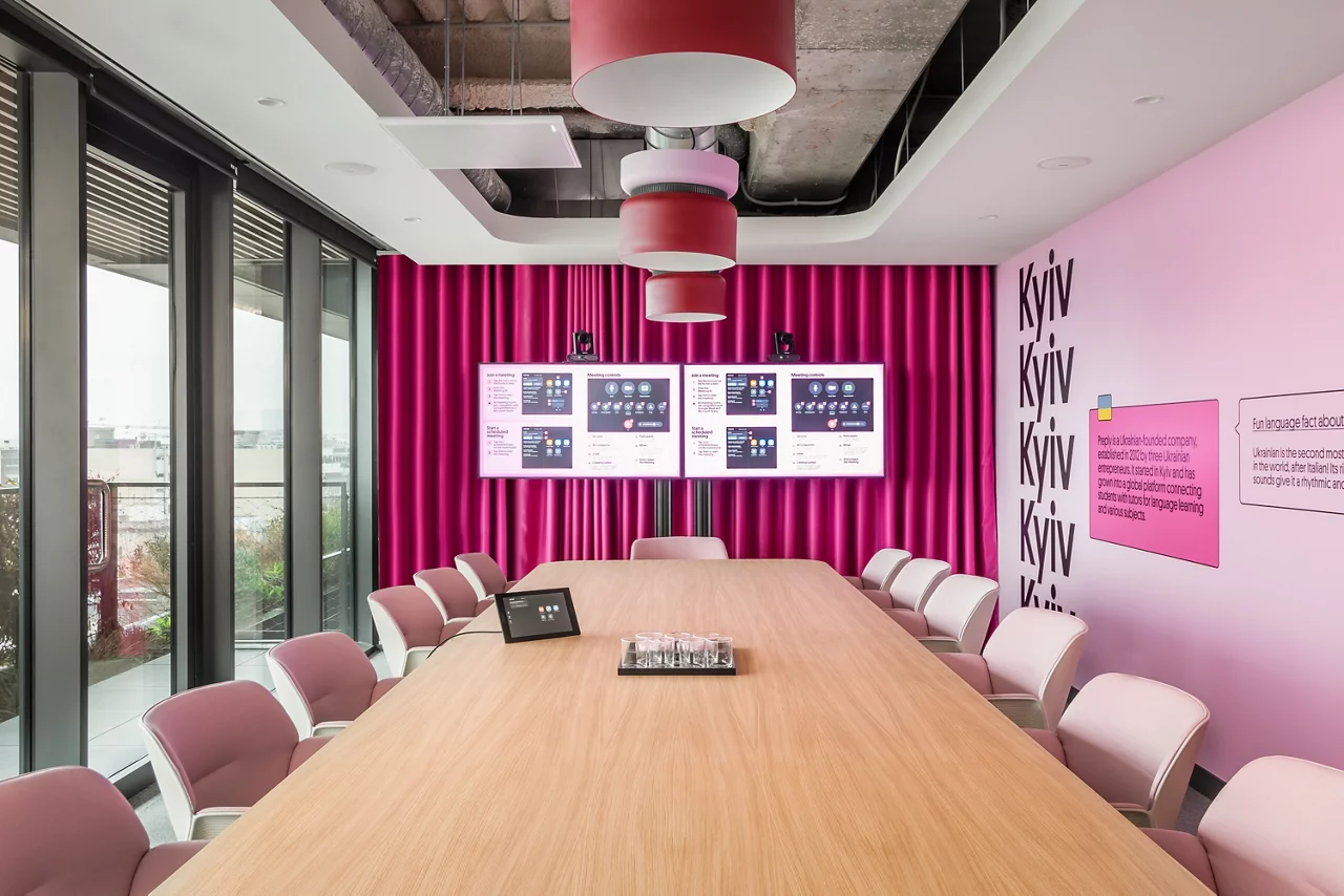 The 'Kyiv' conference room at Preply's office, featuring a long table, pink chairs, and vibrant magenta wall decor.