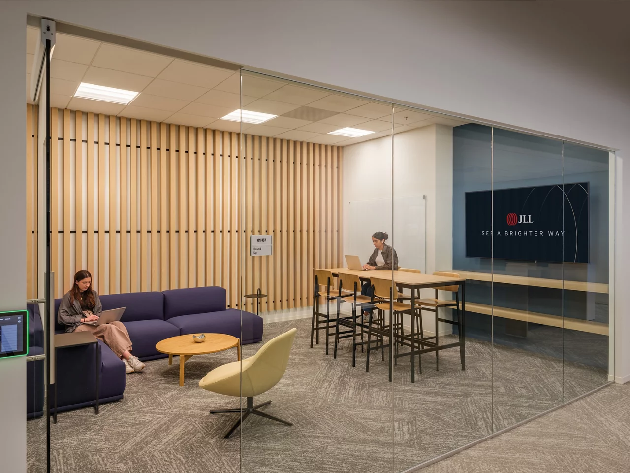 Employees work in a modern, glass-walled collaboration room at the JLL Walnut Creek office.