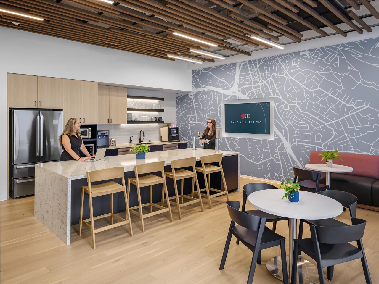 The modern kitchen and cafe in the JLL Walnut Creek office, with an island, seating, and a large city map mural.