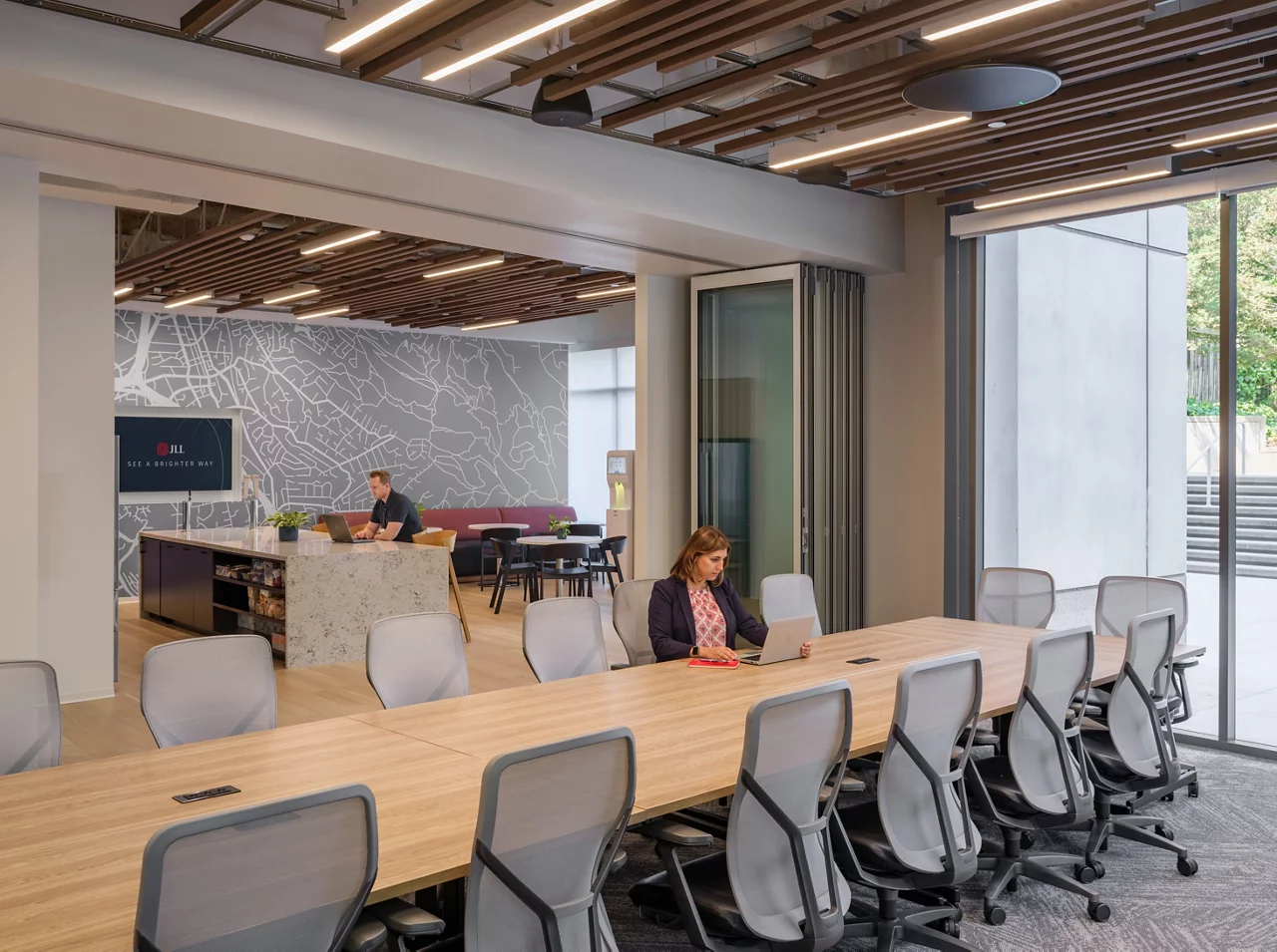 The modern, open-plan JLL Walnut Creek office, showing the conference area flowing into the employee kitchen and cafe.