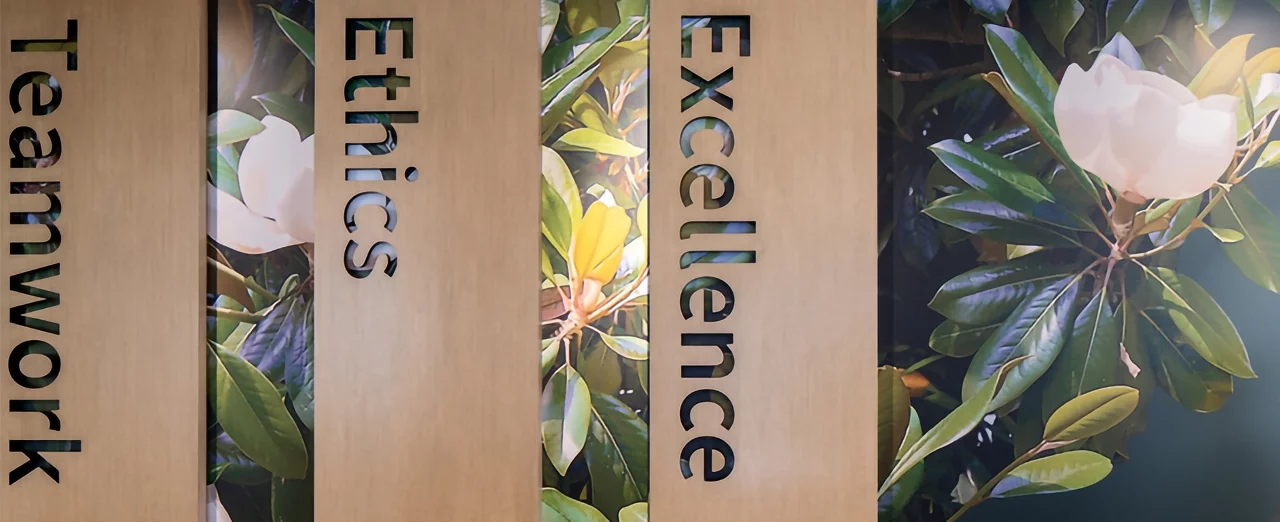A man walks past a wall with the words "Teamwork," "Ethics," and "Excellence" displayed vertically.