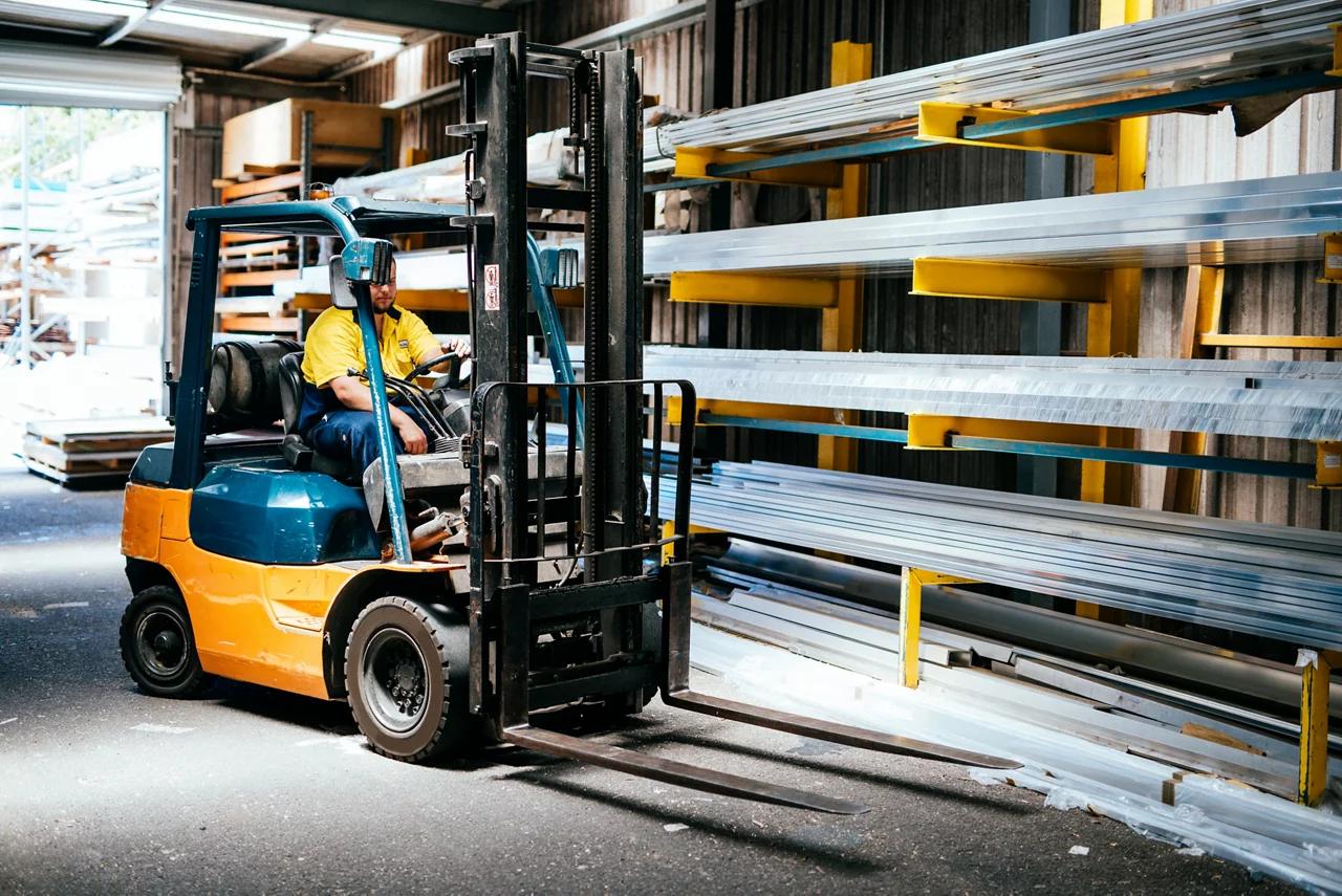 Worker driving forklift in warehouse
