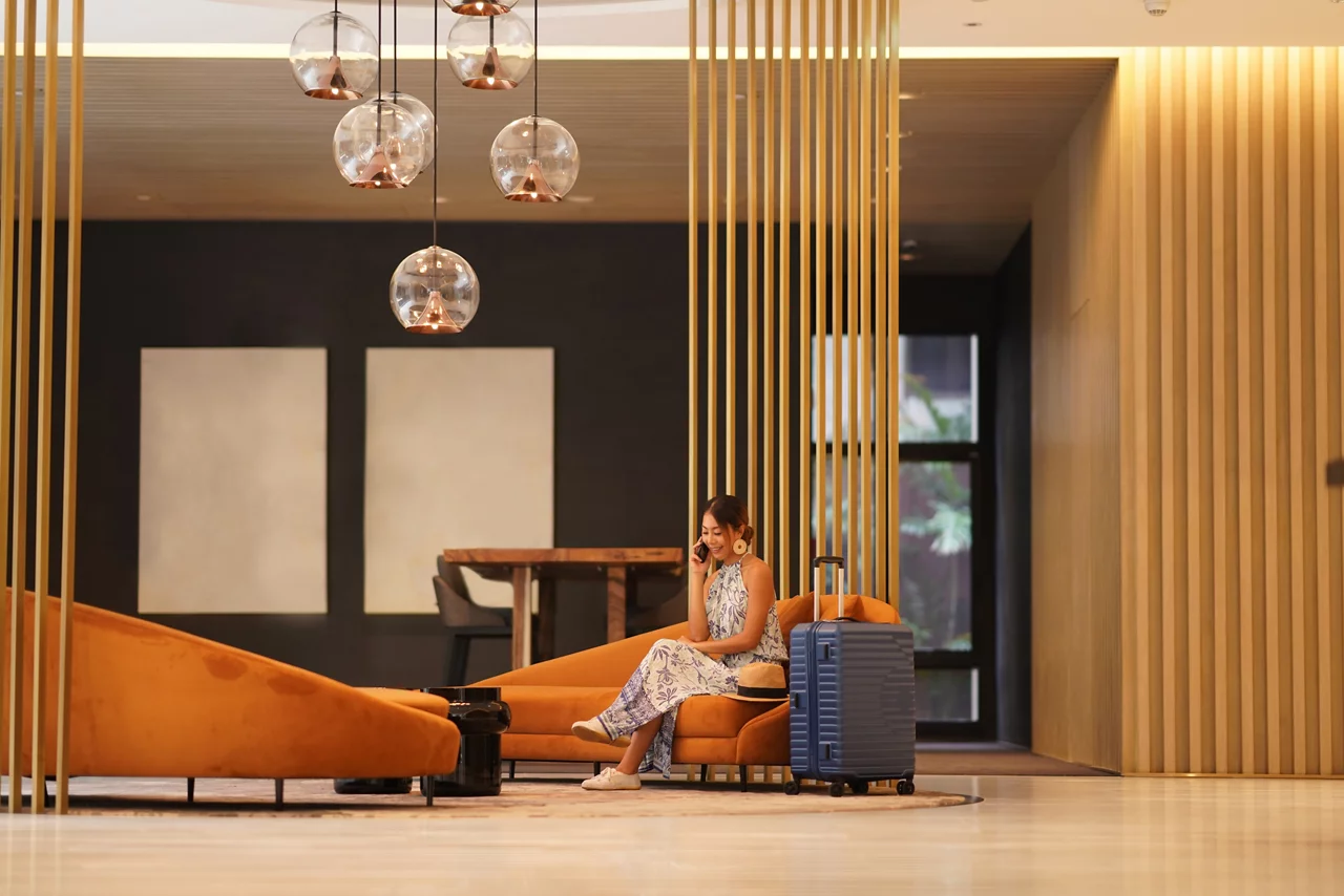 Young tourist woman sitting on sofa at hotel lobby