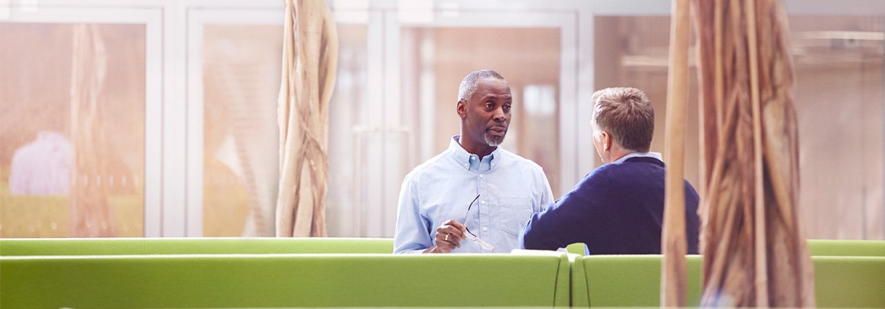 Duas pessoas conversando em um escritório com banco verde