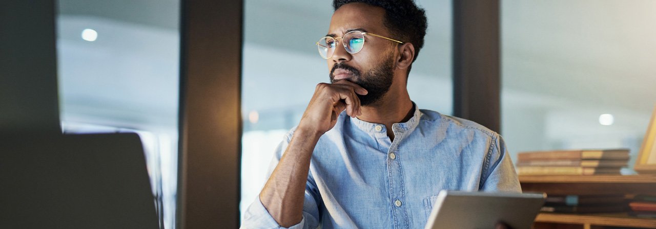 Homem utilizando um tablet e olhando para o notebook