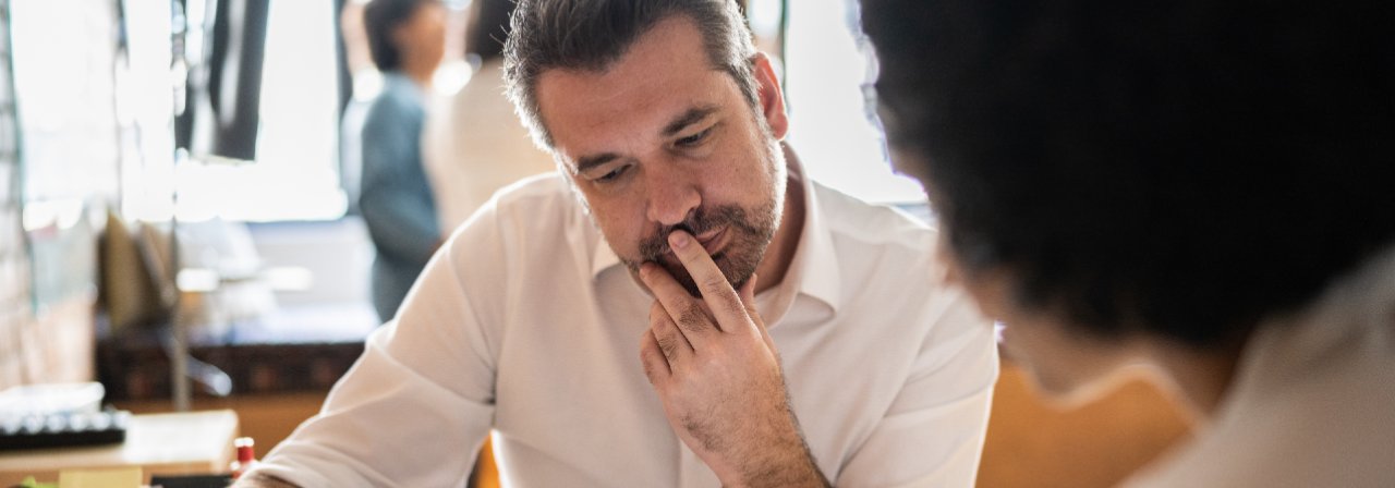 Homem de barba com a mão no queixo, prestando atenção
