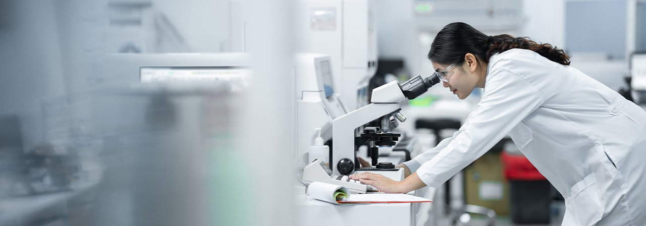 Pesquisadora olhando microscópio em laboratório