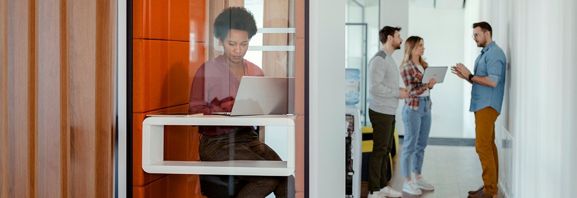 オフィスの防音ブースで電話会議を行う従業員