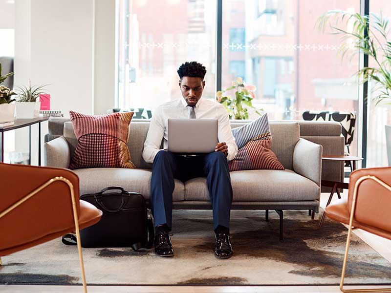 Businessman sitting on sofa working on Laptop
