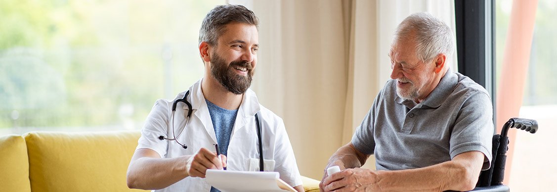 A doctor speaks with an elderly man in a wheelchair, showcasing a supportive and professional healthcare environment.