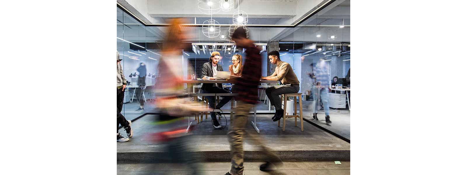 Group of young freelancers working on wireless technology at casual office.
