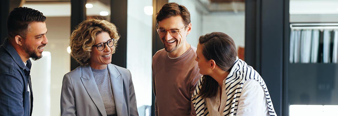 A diverse group of individuals collaborates around a laptop, engaged in discussion and sharing ideas