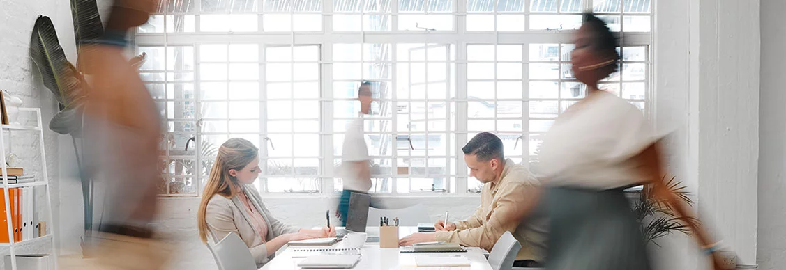 blurry image with people moving and working in a workplace space