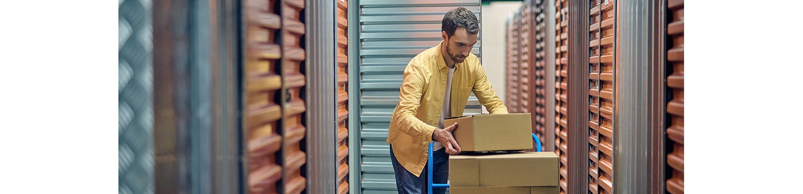 Man loading boxes from a trolley into a self storage unit.