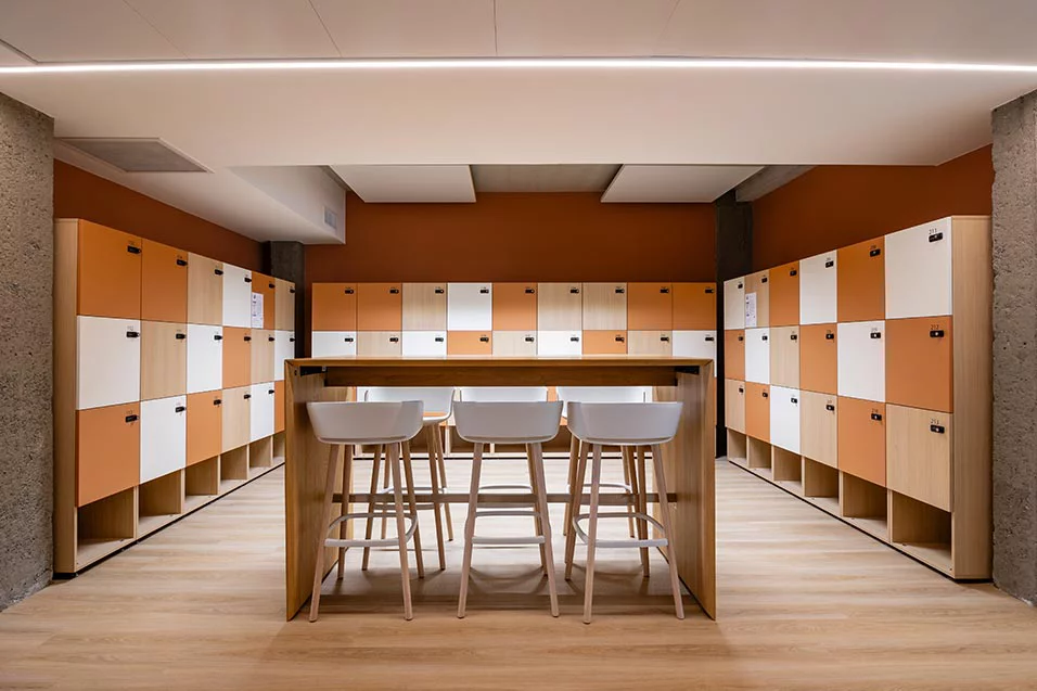 Interior view of a room with vibrant orange and white lockers and stools, creating a lively atmosphere.