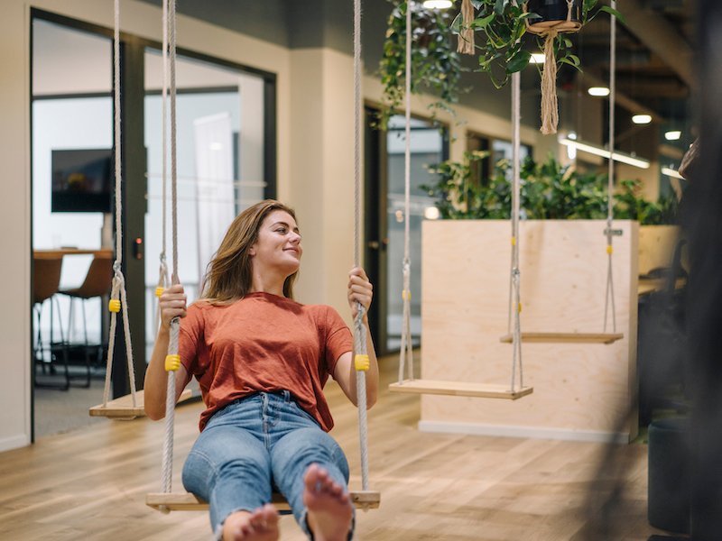 Young woman sitting on swing in an office