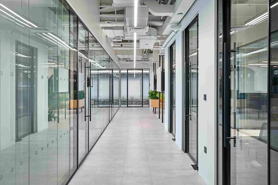 A spacious hallway with glass walls and doors, allowing natural light to illuminate the area.
