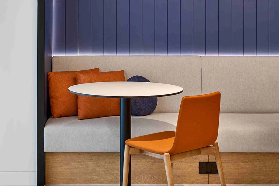 A cozy room featuring a small table and two vibrant orange chairs.