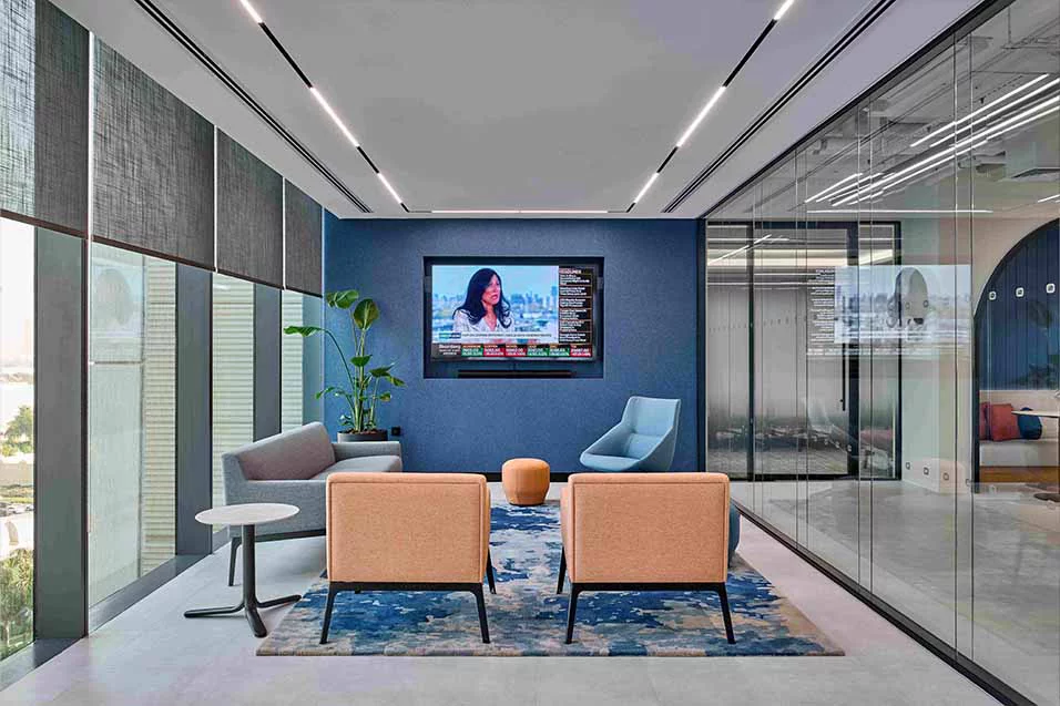 An office featuring blue walls and glass partitions, creating a modern and open workspace environment.