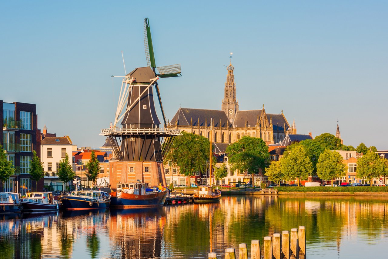 Skyline of Haarlem, North Holland, Netherlands around sunrise, with Windmill "De Adriaan" from 1779 and 13th Century Saint Bavo Church. The Spaarne river flows through Haarlem.