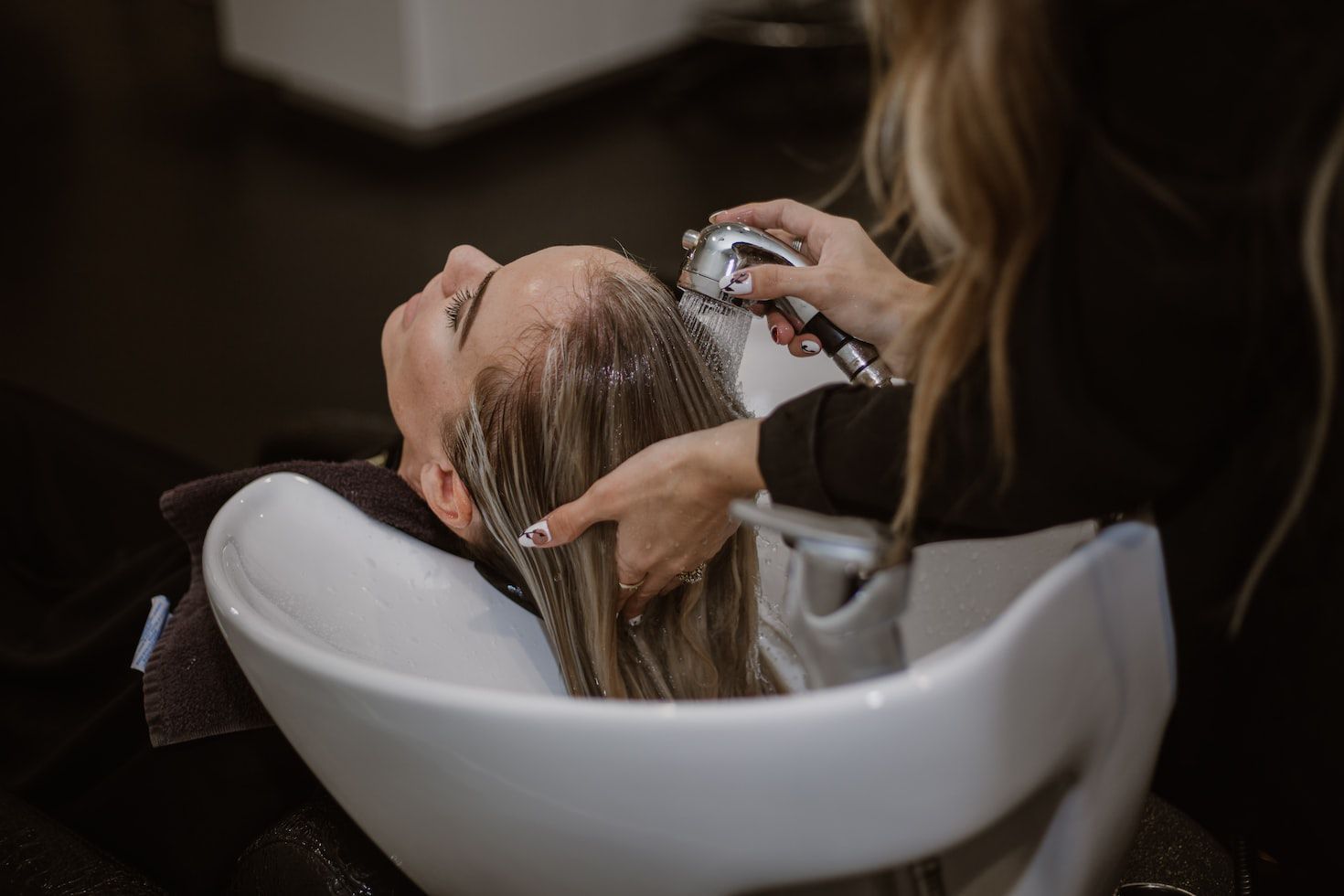 a woman getting her hair washed by a hair stylist.