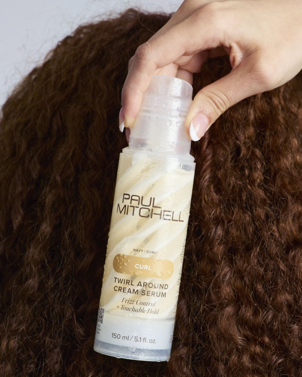 image of woman holding a bottle of Twirl Around Styling Cream Serum