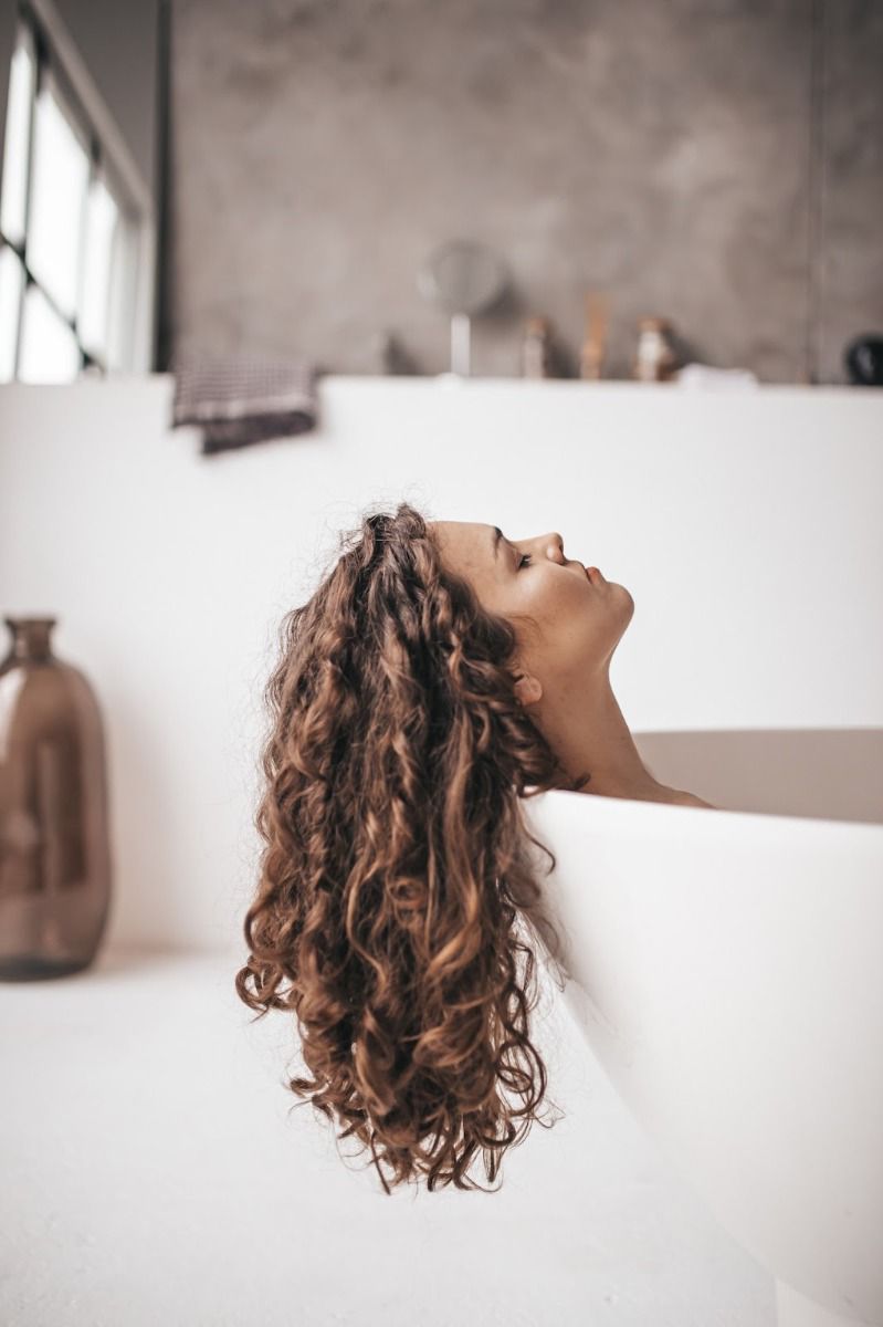 image of a woman with curly brown hair in a bathtub