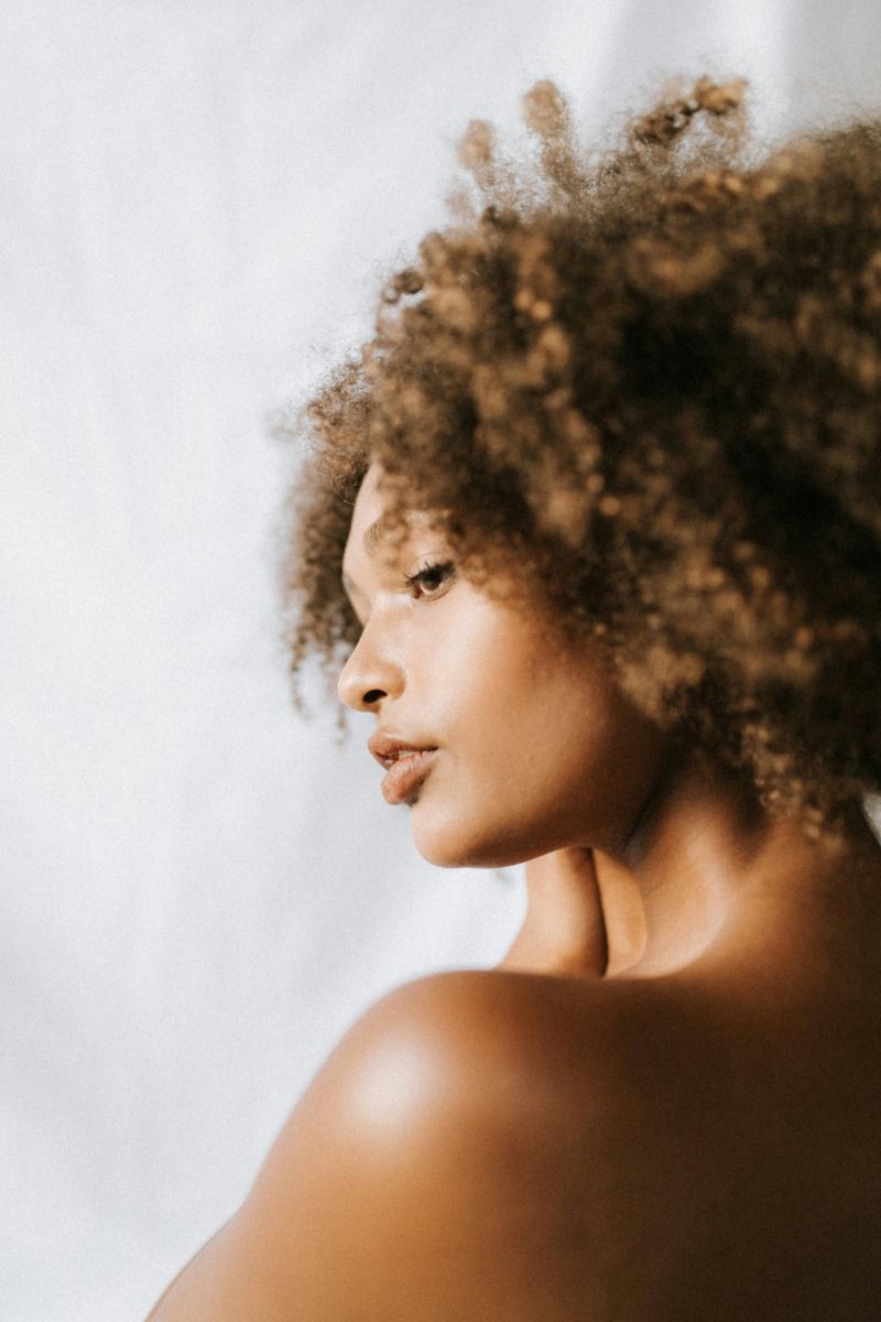 a woman with brown curly hair looking over her shoulder