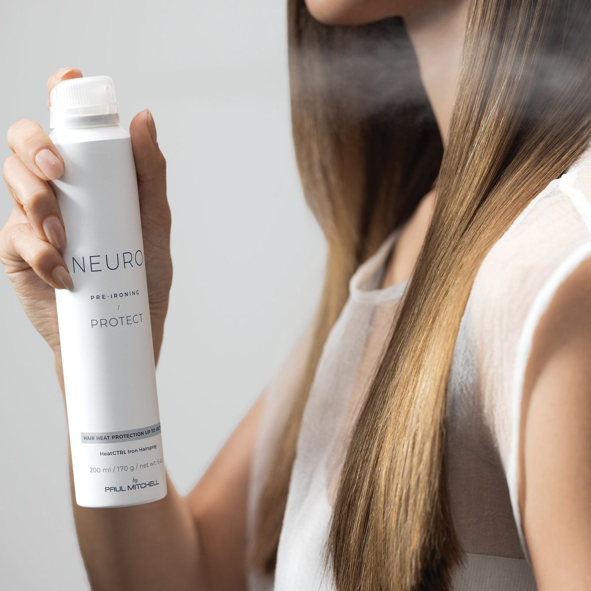 image of a woman spraying Neuro Protect on her hair