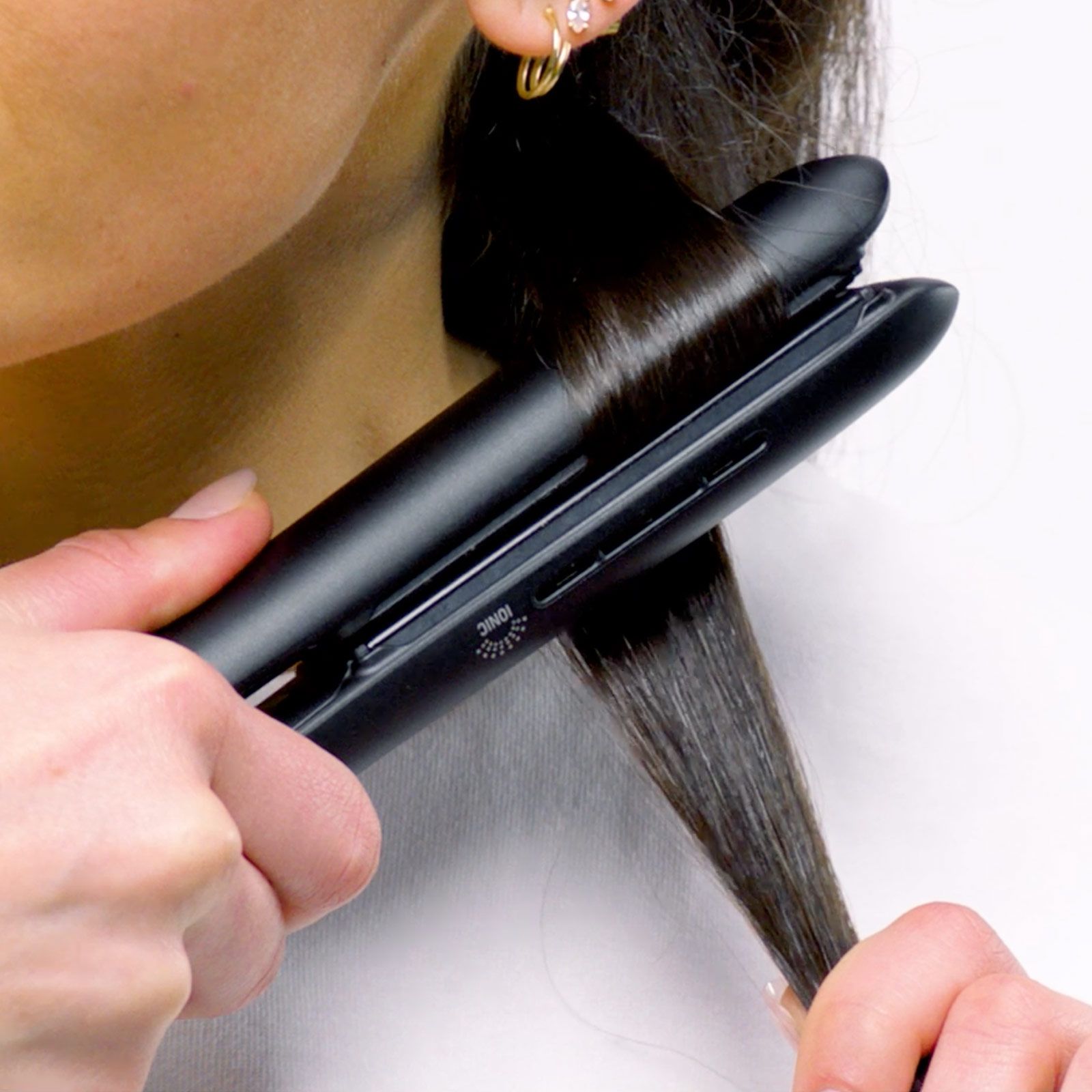 close-up image of a woman using a flat iron