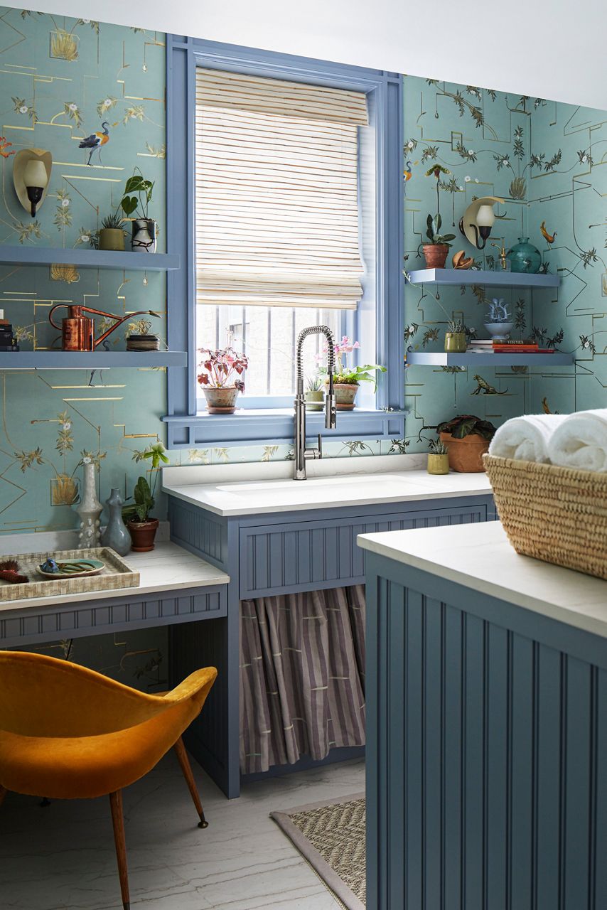 A laundry room with a stainless steel semi-professional faucet and wallpaper with gold accents.