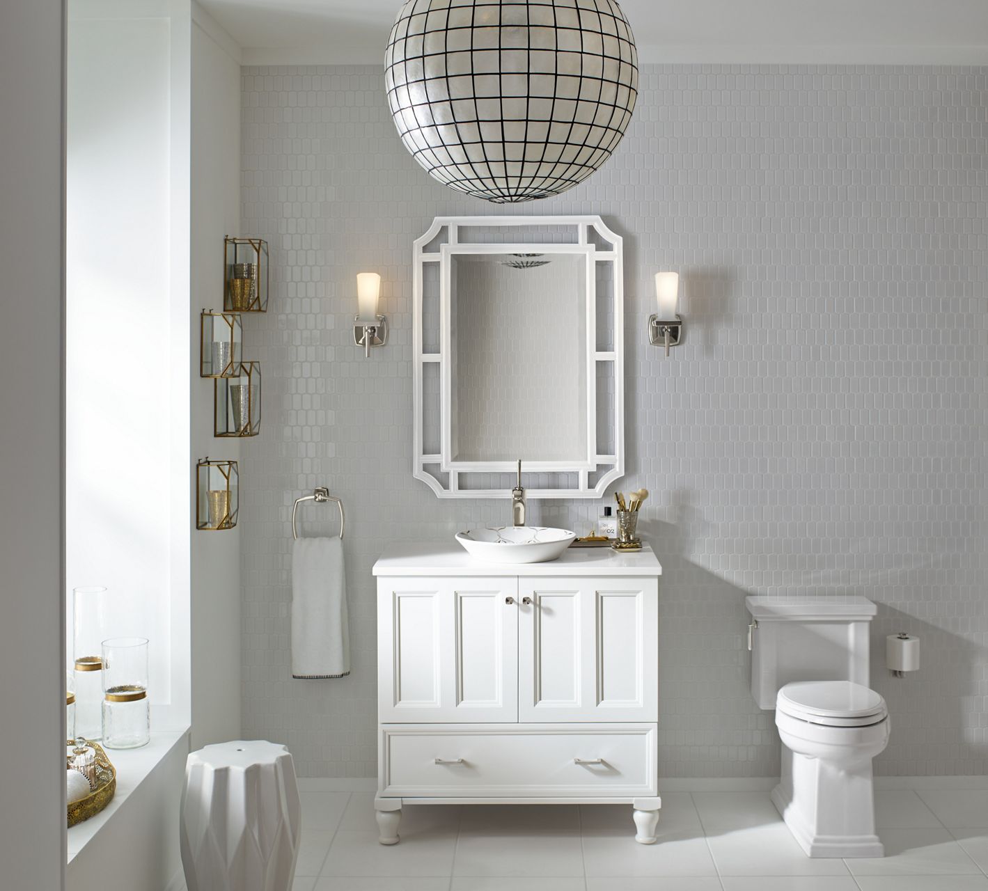 A transitional white bathroom gets contrast from gridded round light fixture, a patterned mirror frame, and architectural details on the vanity and toilet