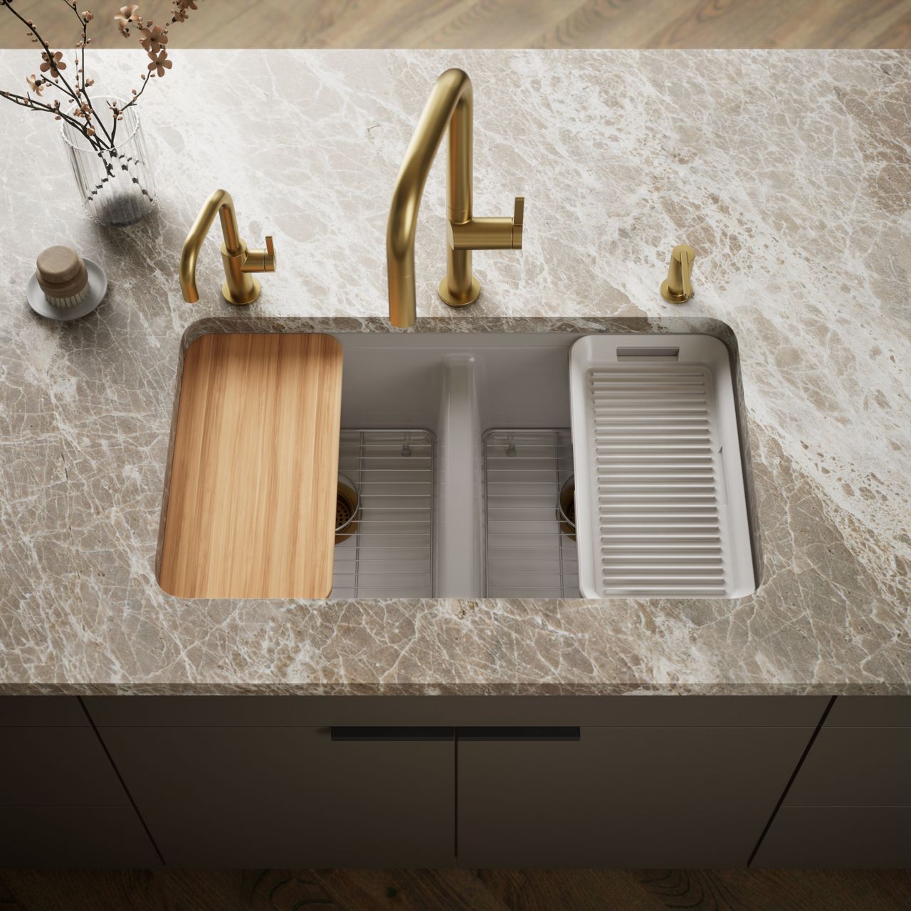 Contemporary double-bowl stainless steel kitchen sink with a brass pull-down faucet, wooden cutting board, and drying rack on a marble-look countertop.