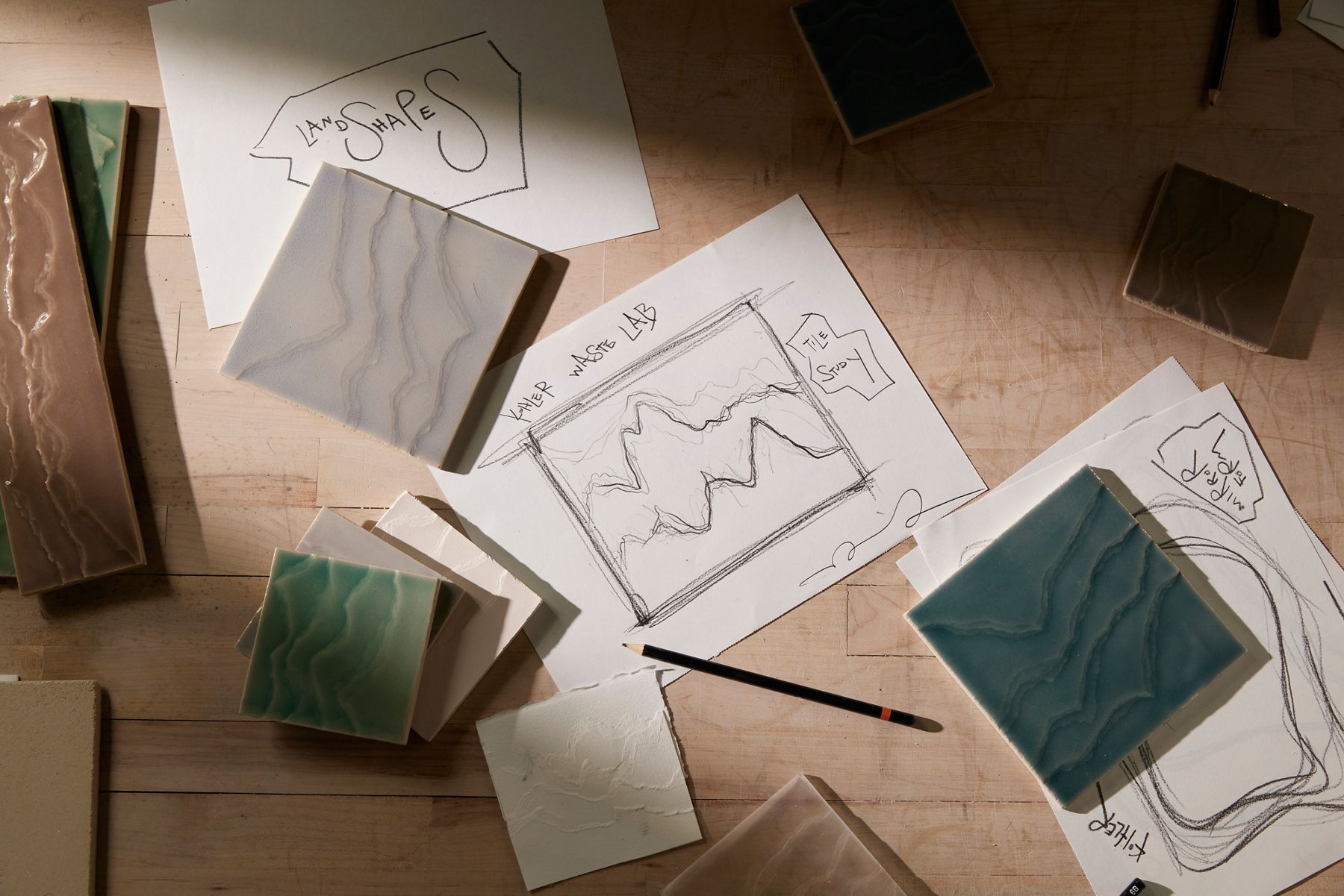 Assortment of marble samples and sketches laid out on a wooden design table.