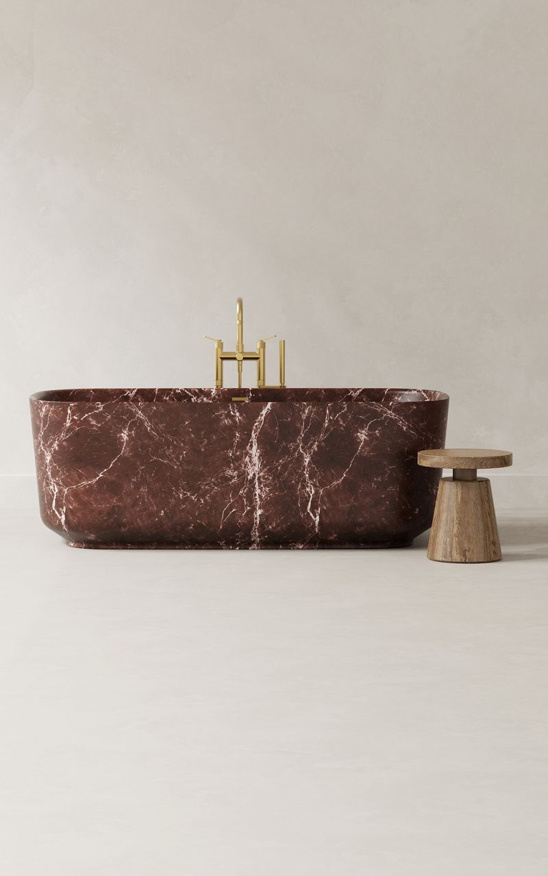 Luxurious freestanding bathtub in polished dark red marble with minimalist stool.
