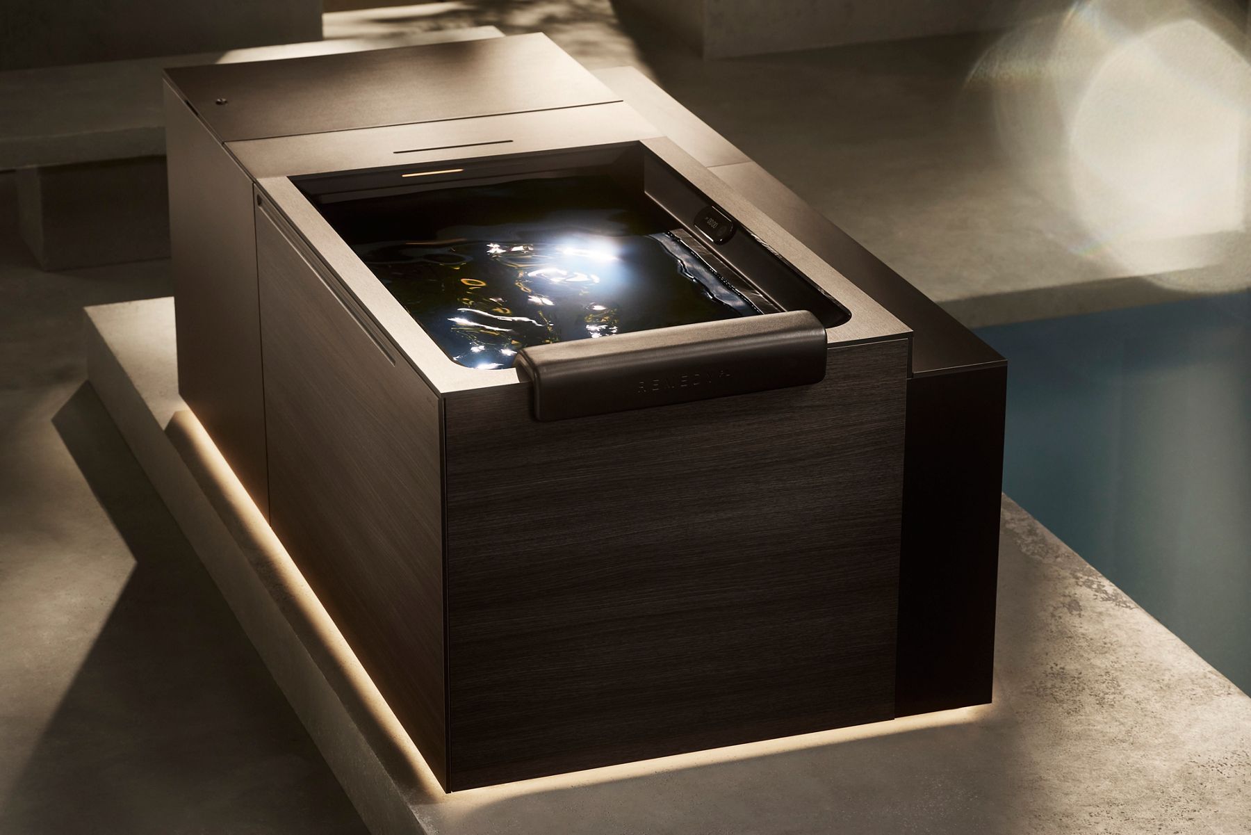 Modern, square, dark wood hot tub with built-in controls, illuminated from below.