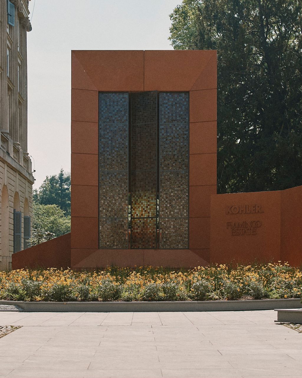 The outside of the Flamingo Estate Bathhouse by Kohler, a bold 247-square-foot monolithic structure that appears to emerge organically from a meadow of wildflowers.