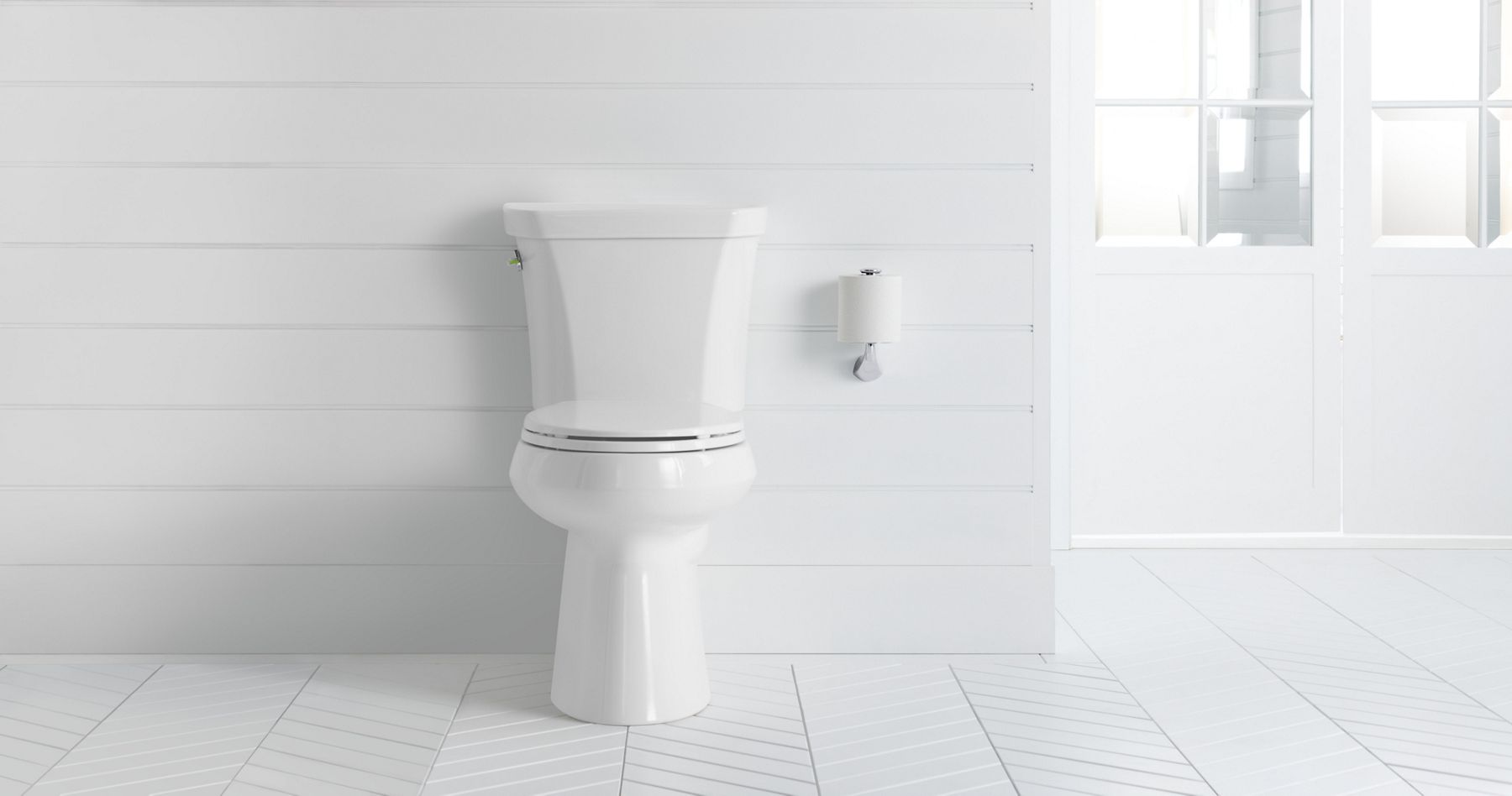 A white bathroom with a white KOHLER Highline elongated dual-flush toilet.