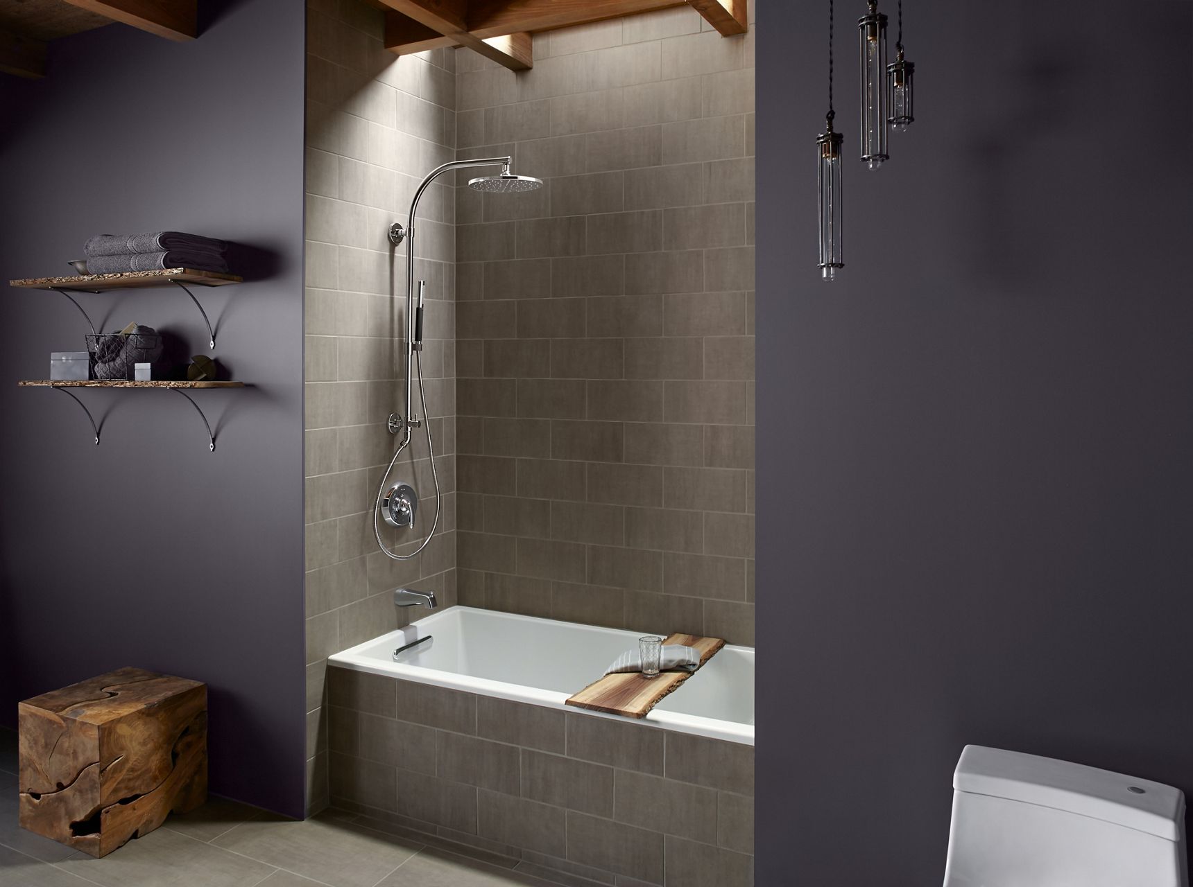 Une douche carrelée avec colonne de douche HydroRail de KOHLER et pomme de douche à effet de pluie.