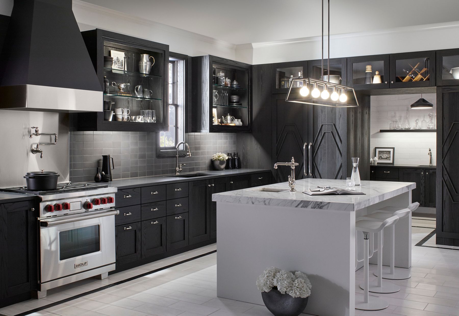 Modern black kitchen featuring a white island with an integrated sink and chrome faucet.
