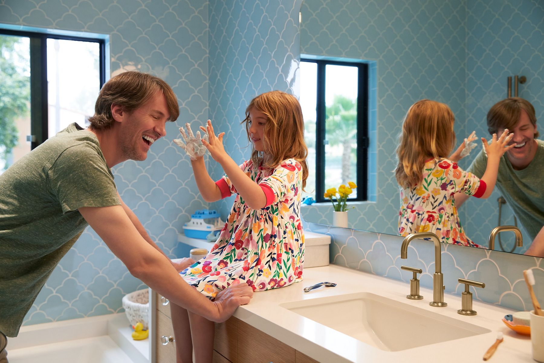 A father laughs with his daughter in a kid's bathroom with KOHLER bath products