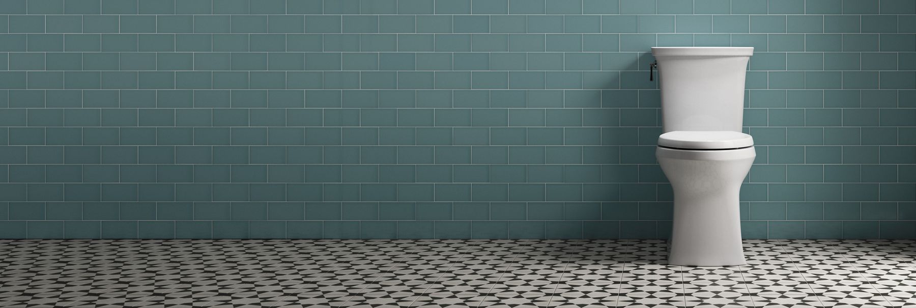 Kohler skirted toilet in front of green tile wall