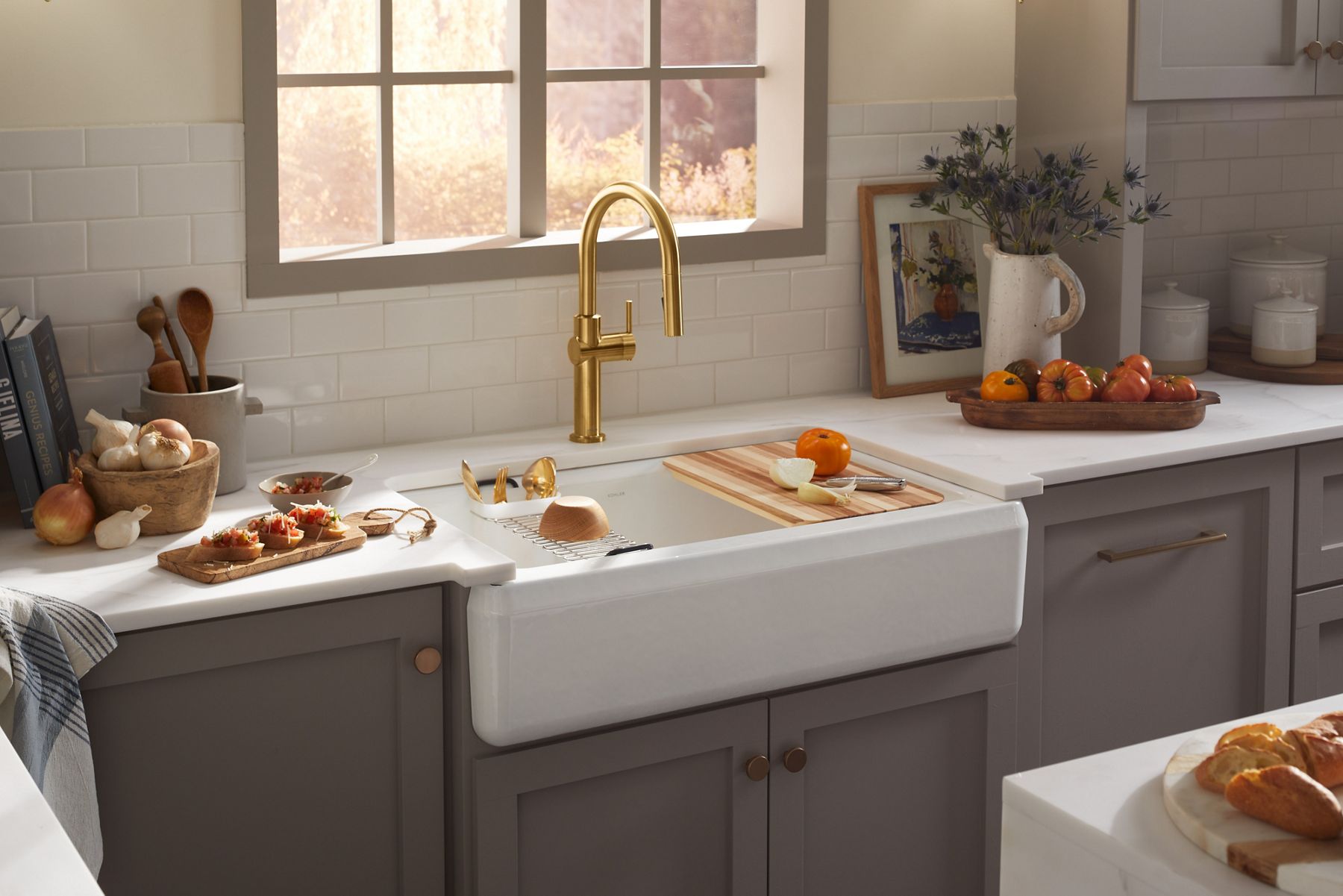 An apron front workstation sink with a cutting board and other accessories on its internal ledges.