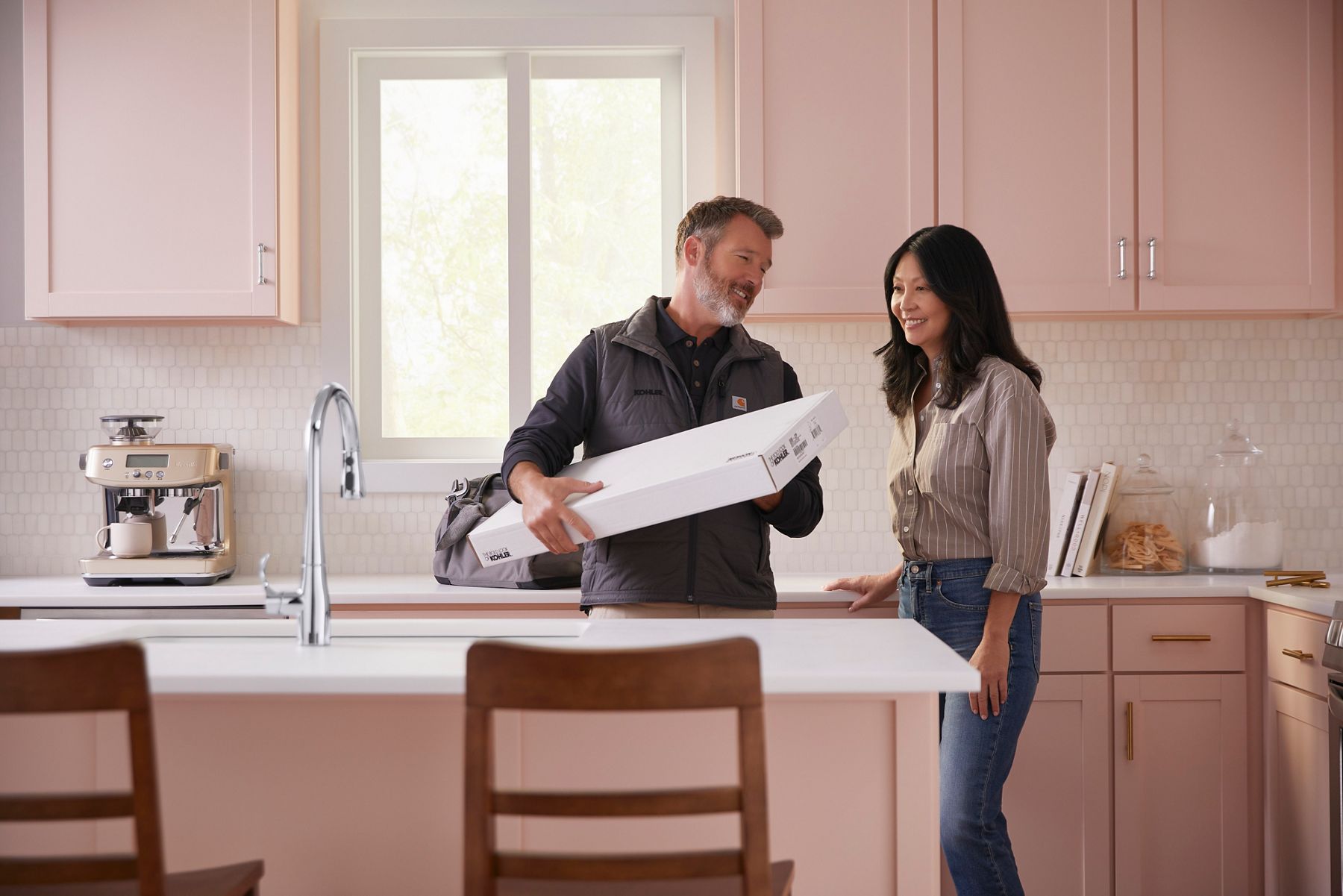 Man and woman discussing sustainable packaging while holding a white product box, representing Kohler's packaging ambition for recyclable and reusable materials.