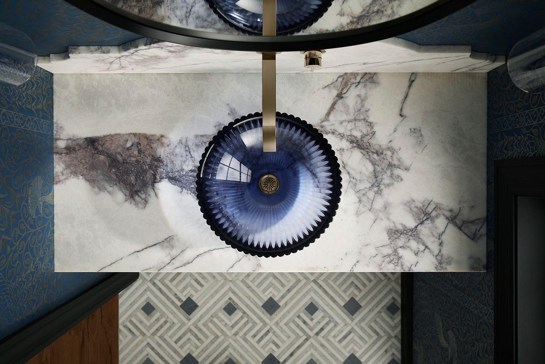 Overhead view of a blue round glass sink with fluted edges.