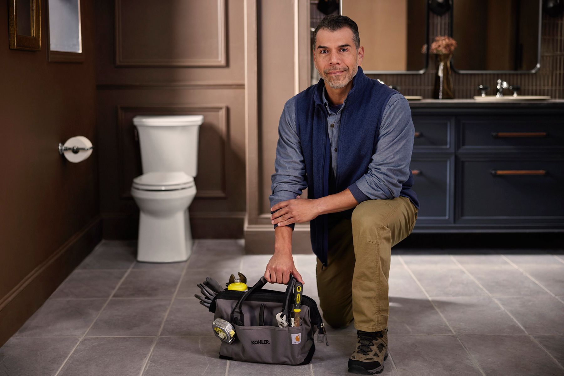 Kohler installation expert kneeling in a bathroom with his toolkit.